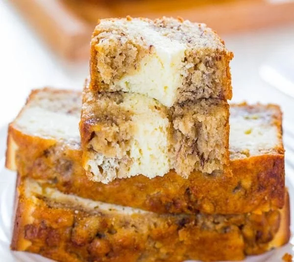 Delicious cream cheese-filled banana bread loaf sliced on a wooden board