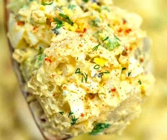A bowl of deviled egg potato salad garnished with paprika and herbs.