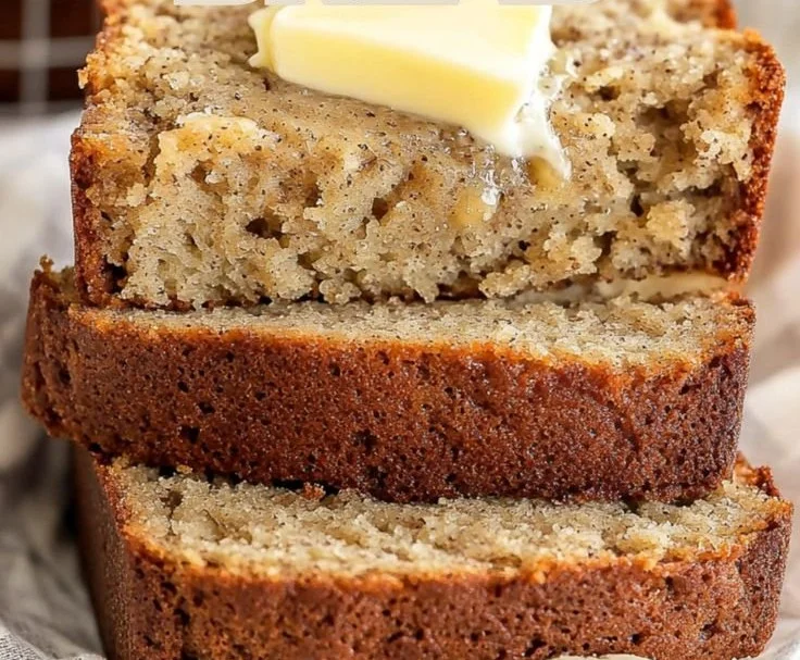 Slice of easy moist banana bread on a plate with bananas in the background