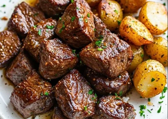 Garlic Steak Bites served with crispy potatoes on a plate