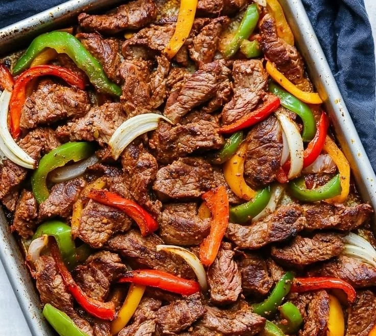 Sheet pan skirt steak fajitas with bell peppers and onions ready to serve.
